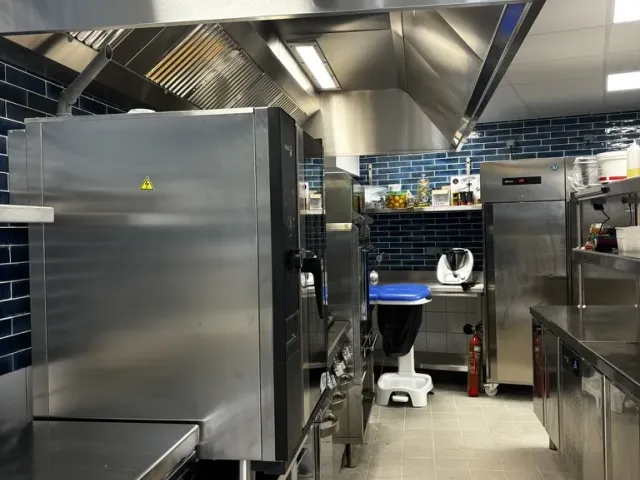 Après travaux : cuisine livrée, hotte et four inox devant une crédence de zelliges bleus.