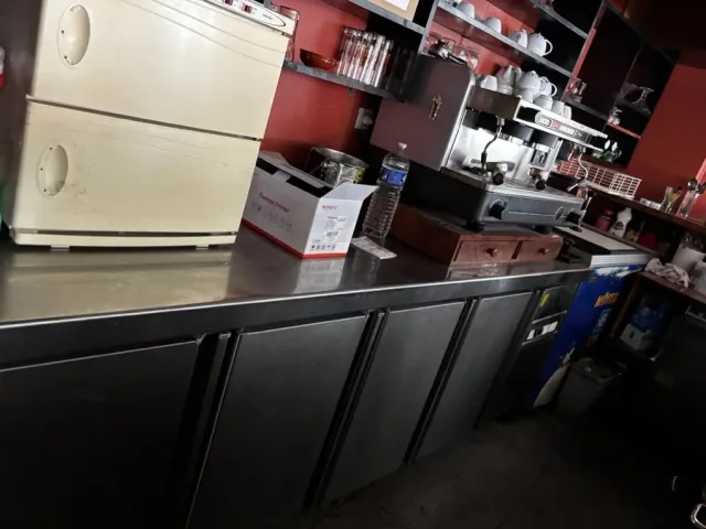 Avant travaux : arrière-bar existant, meubles sombres et machine à café.