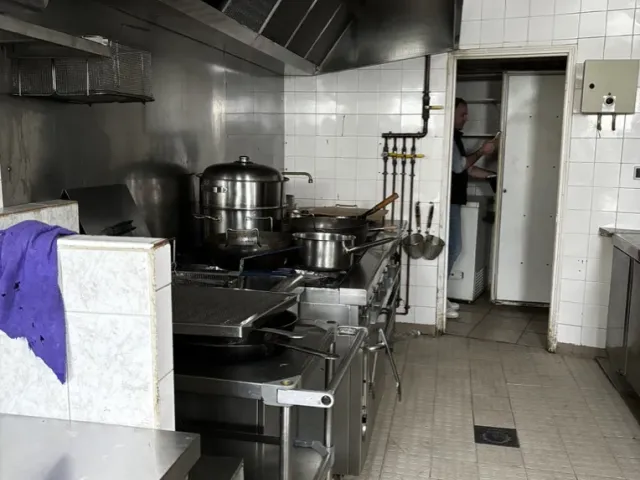 Avant travaux : ancienne cuisine, hotte et plans inox sur carrelage blanc.