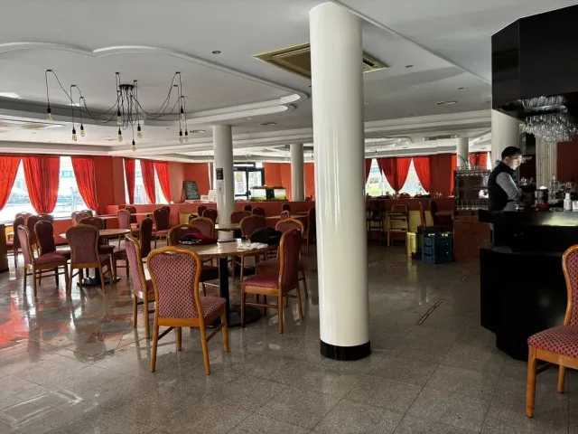 Avant travaux : la salle avec son mobilier ancien, colonne centrale et rideaux rouges.