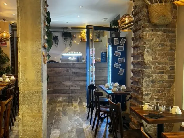 Après travaux : salle livrée, pierre apparente, suspensions en rotin et tables en bois.