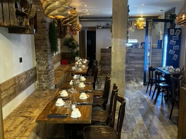 Après travaux : enfilade de tables le long du mur de pierre, sous les suspensions.