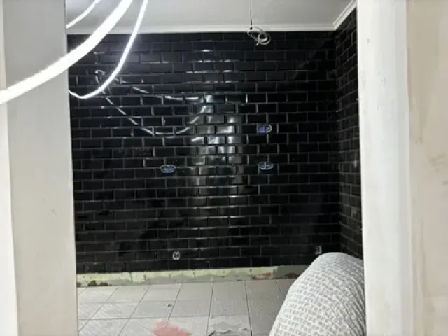 Avant travaux : mur de zelliges noirs existant et sol carrelé blanc.