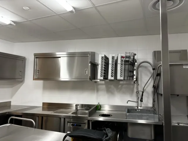 Après travaux : plonge inox équipée de sa douchette, meubles hauts et crédence.