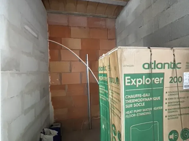 Avant travaux : réserve en parpaings, chauffe-eau encore emballé posé au sol.
