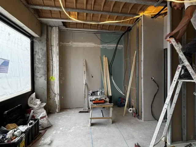 Chantier : second œuvre en cours sous le plafond à hourdis, échelle et réseaux tirés.