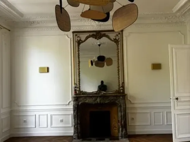 Cheminée de marbre d’origine et trumeau à miroir conservés, encadrés de boiseries repeintes en blanc.