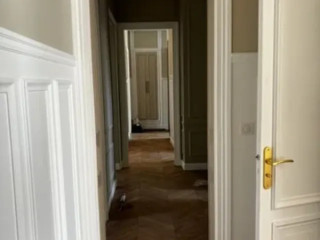 Enfilade de pièces rénovées vue depuis le couloir, portes à panneaux et parquet à bâtons rompus dans l’axe.
