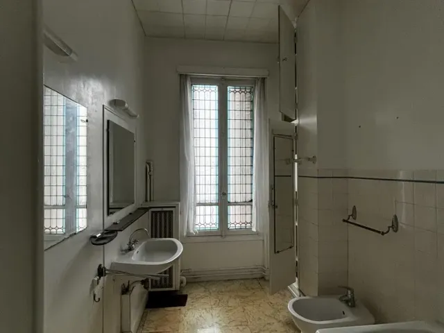 Salle de bains avant travaux : faux plafond en dalles, carrelage à frise, baignoire encoffrée, bidet et lavabo d’origine.