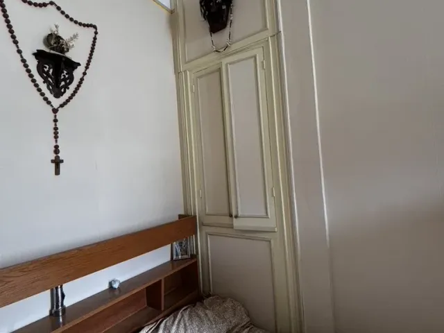 Chambre occupée avant travaux, placard mural d’origine et faux plafond en dalles.